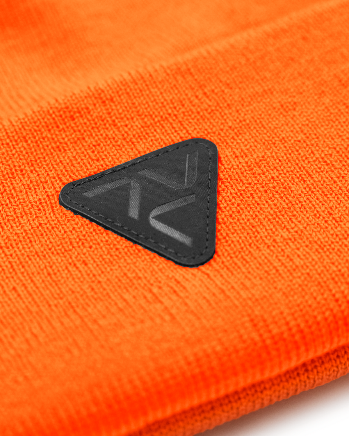 Close-up of VOHL Beanie in Safety Orange showing black triangular logo patch and knit texture - SKU AC-BN-200