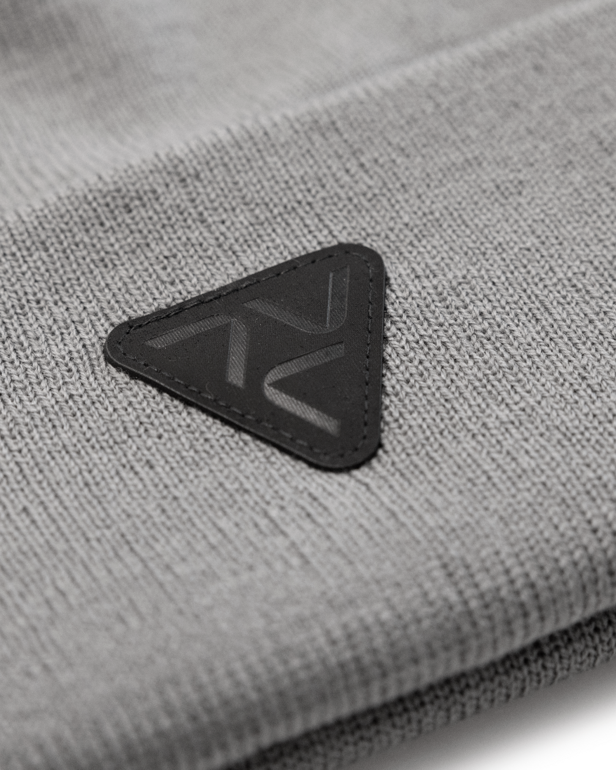 Close-up of VOHL Beanie in Pewter showing black triangular logo patch and knit texture - SKU AC-BN-700