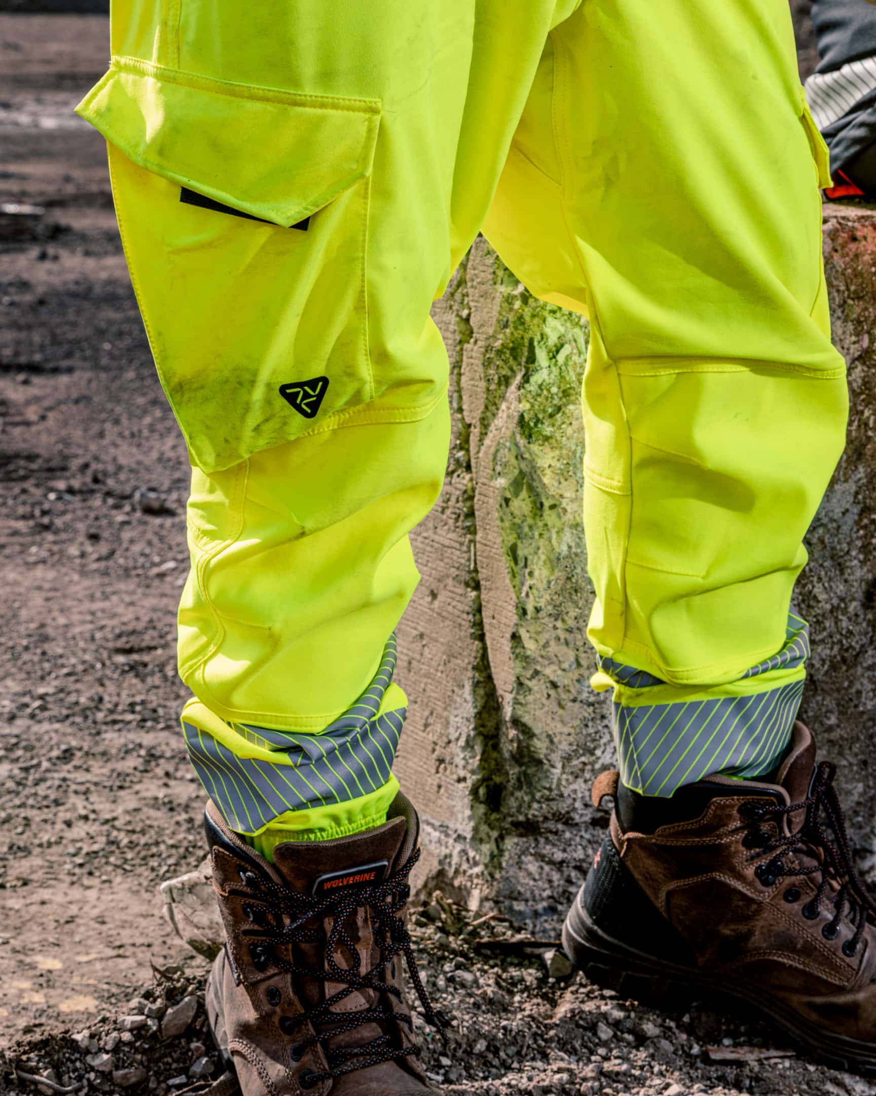 Close-up of hi-vis yellow jogger work pants with cargo pocket, reinforced knees, and reflective cuffs worn with work boots – SKU HV-JG-105 | color:safety-yellow