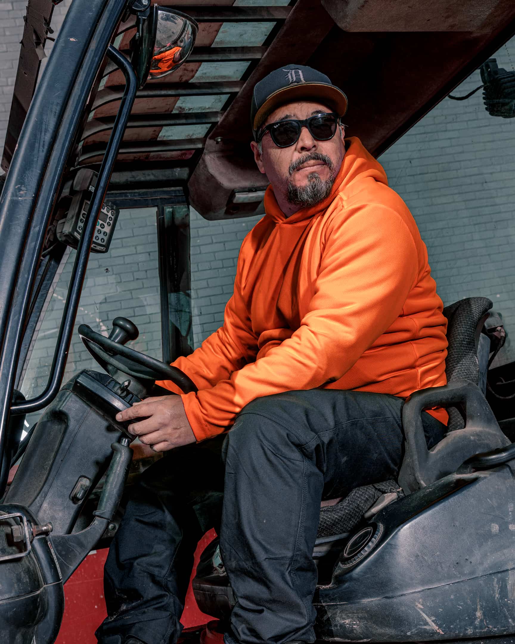 Man wearing hi-vis orange long sleeve sun hoody seated in machinery cab – SKU HV-SH-200 | color:safety-orange