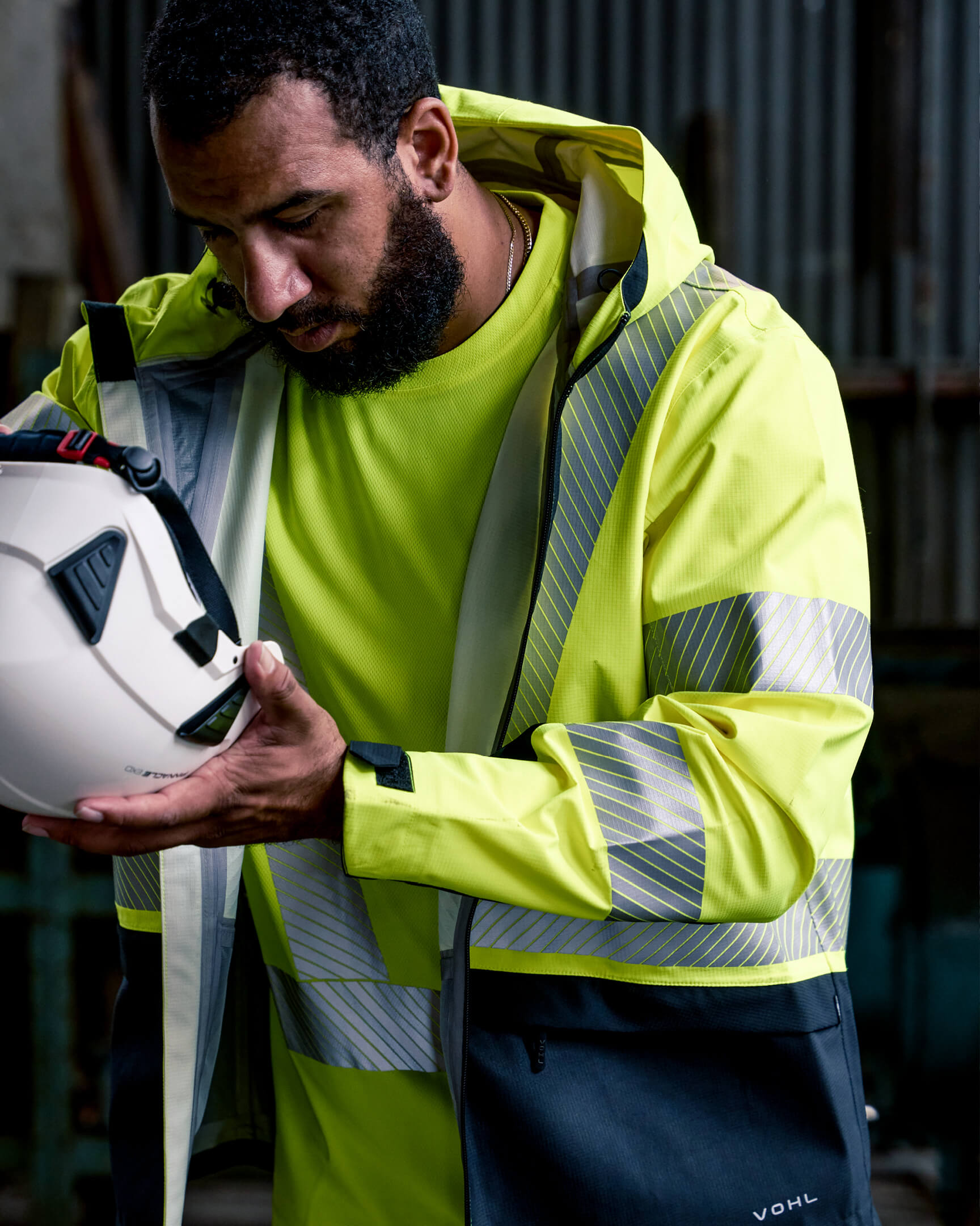 VOHL Hi Vis Waterproof Shell Jacket – Safety Yellow worn while climbing a ladder, demonstrating unrestricted movement and visibility | color:safety-yellow