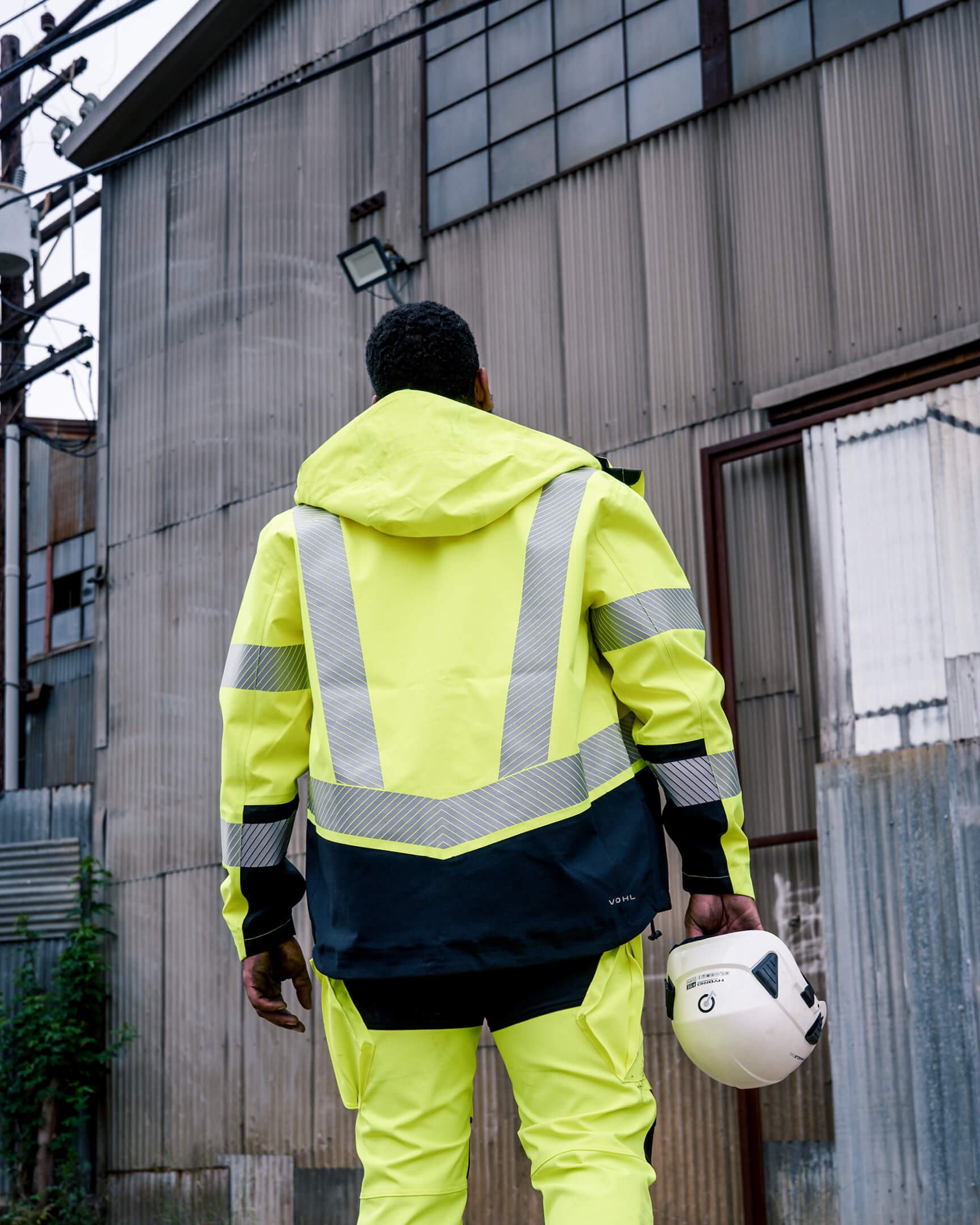 VOHL Hi Vis Waterproof Shell Jacket – Safety Yellow in an industrial environment, highlighting waterproof protection and reflective panels | color:safety-yellow