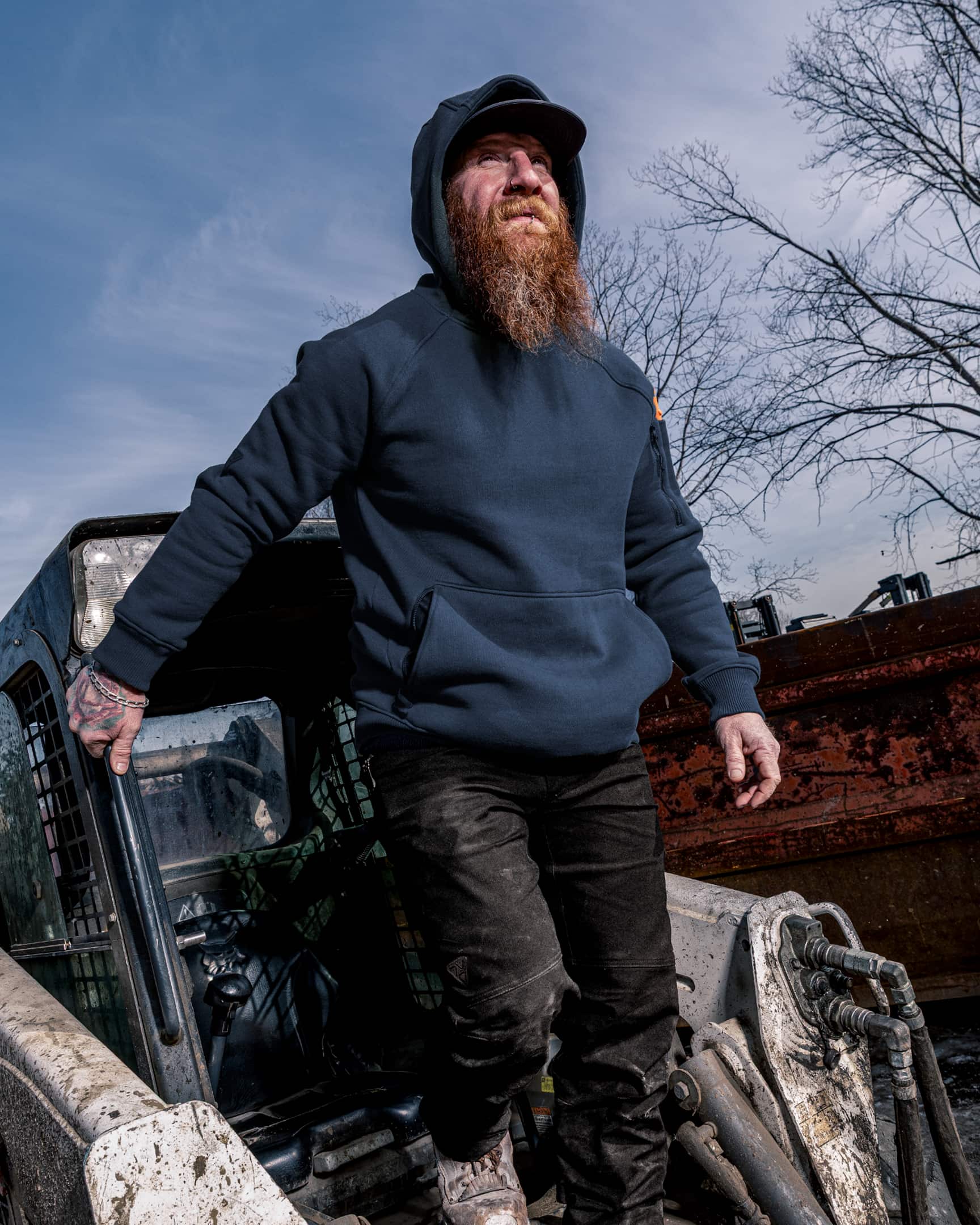 Men’s heavyweight fleece hoody in blue worn on construction site, stepping out of machinery – SKU WW-PO-600 | color:detroit-blue