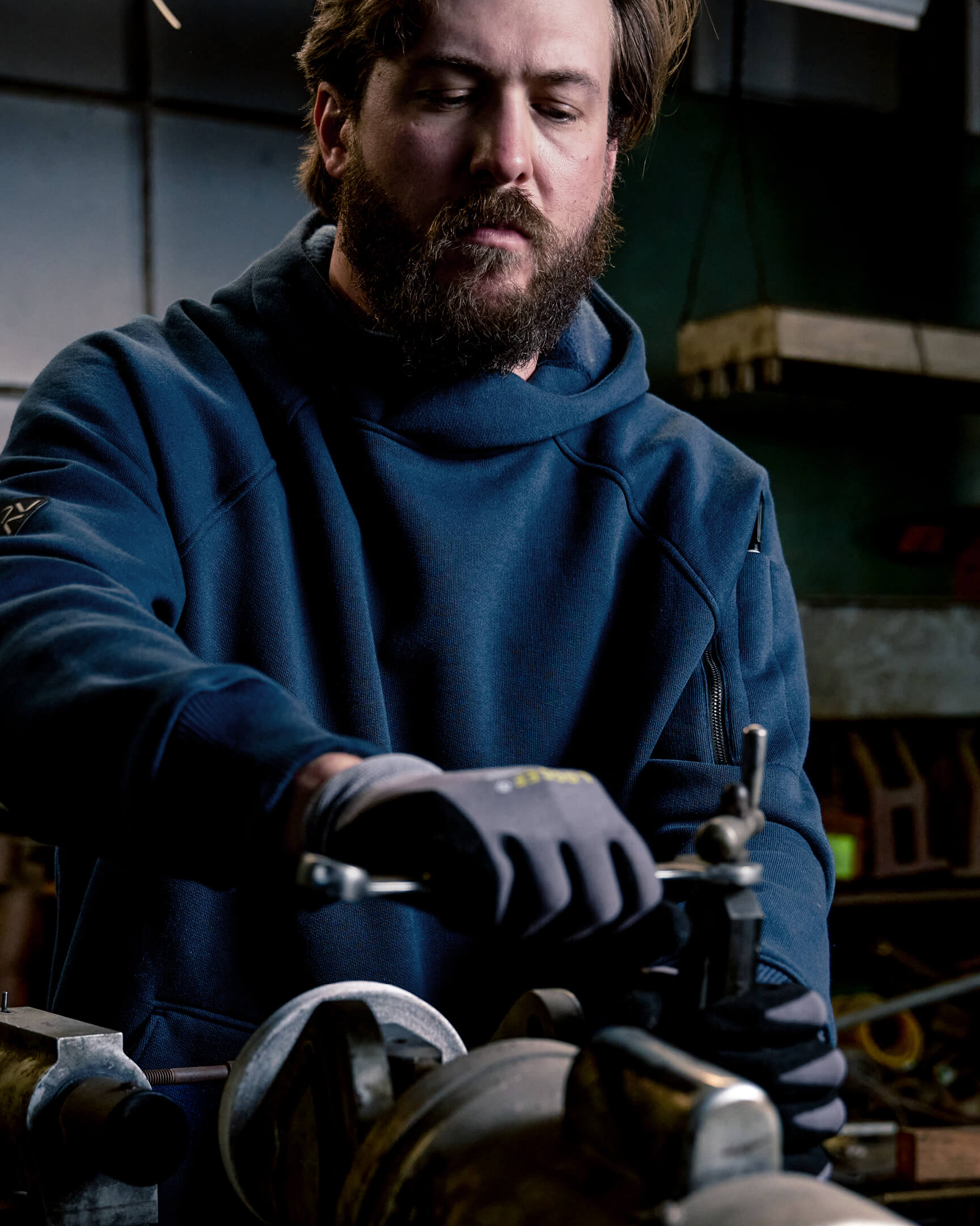 Worker operating machinery while wearing the VOHL Heavyweight Fleece Hoody – Detroit Blue | color:detroit-blue