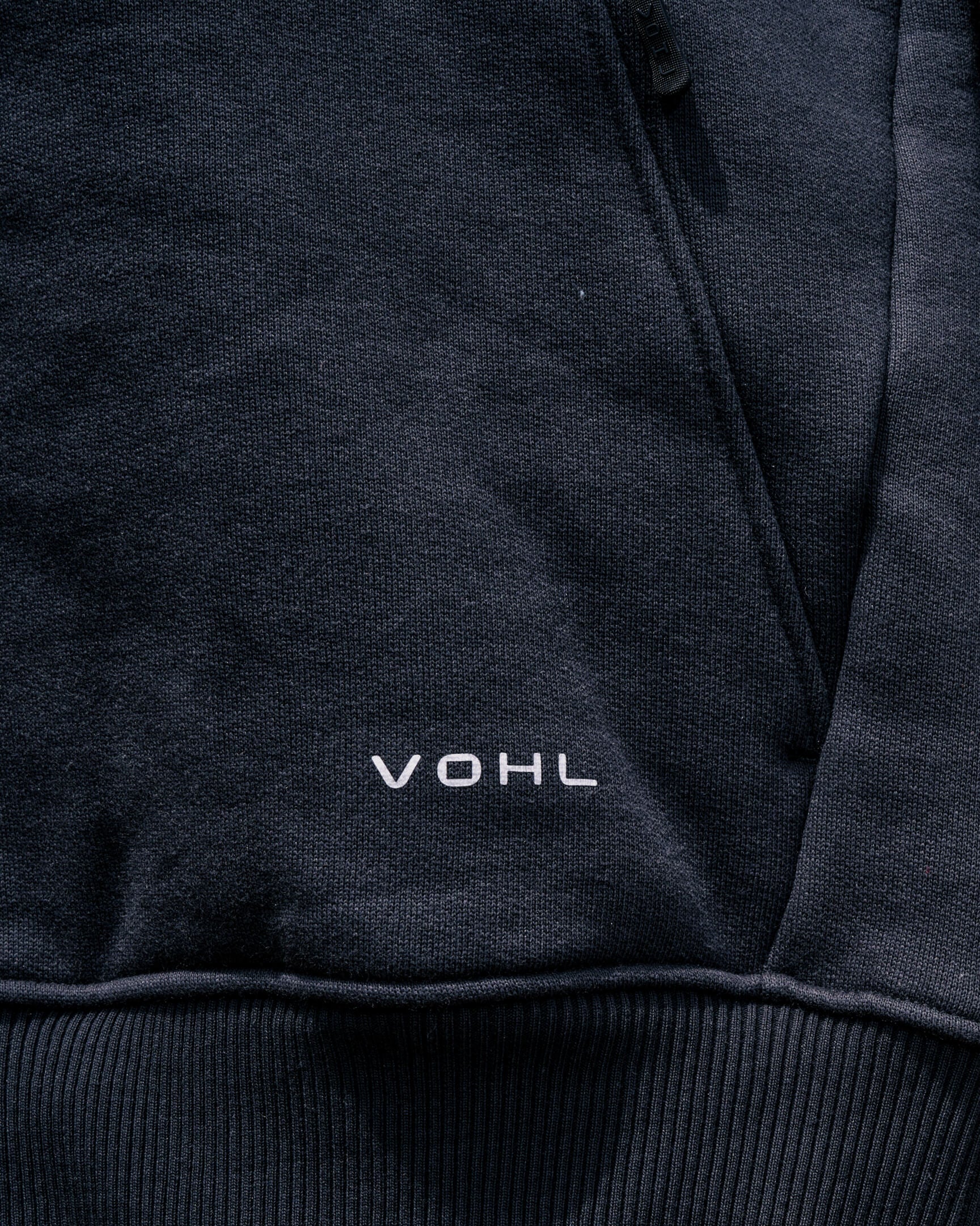 VOHL Heavyweight Fleece Hoody – Black showing the front pocket and logo in a detailed close-up | color:black