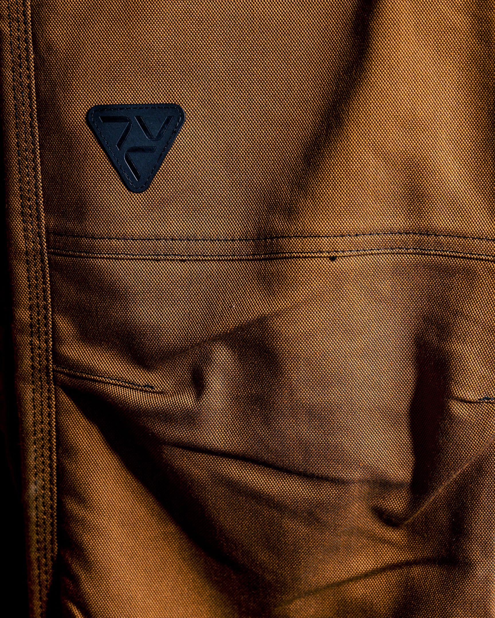 Close-up of the VOHL Straight Leg Pant – Tobacco showing the rear utility pocket and branded patch | color:tobacco